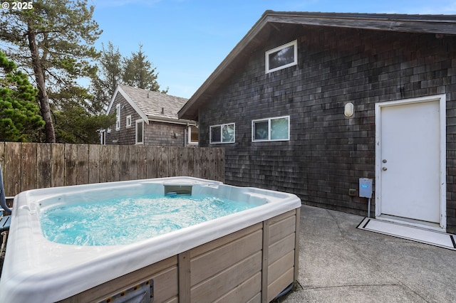 view of swimming pool with fence and a hot tub