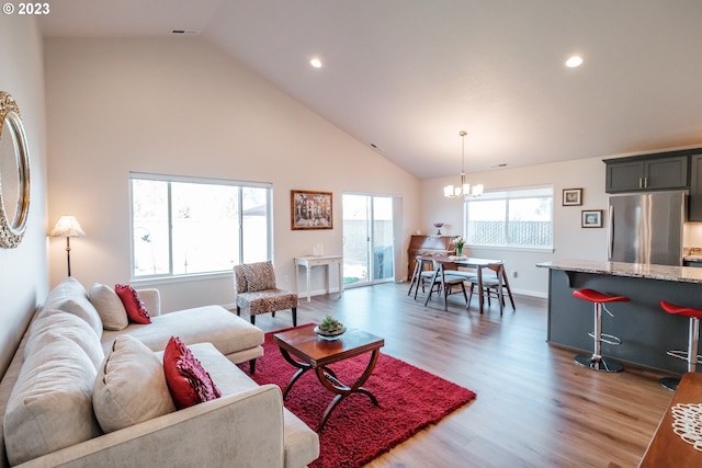 living room featuring high vaulted ceiling, hardwood / wood-style flooring, and a chandelier