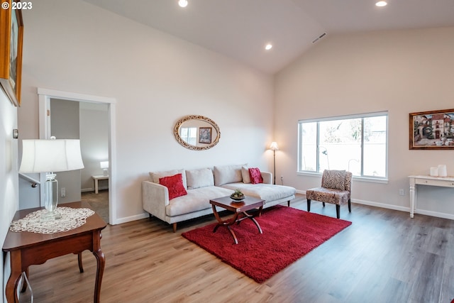 living room with high vaulted ceiling and light wood-type flooring