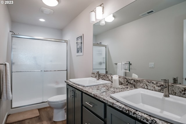 bathroom with toilet, a shower with shower door, vanity, and wood-type flooring