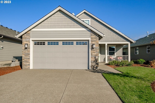 craftsman house with covered porch, a garage, and a front lawn