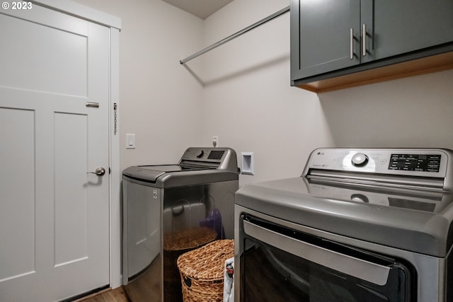 washroom with independent washer and dryer, hardwood / wood-style flooring, and cabinets