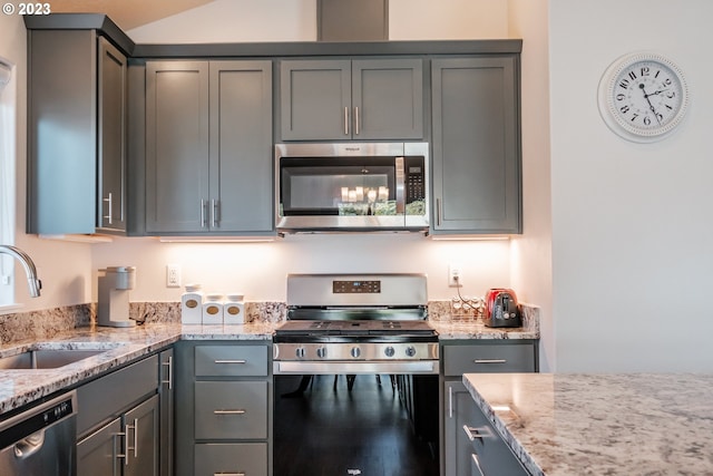 kitchen with sink, light stone countertops, gray cabinetry, and stainless steel appliances