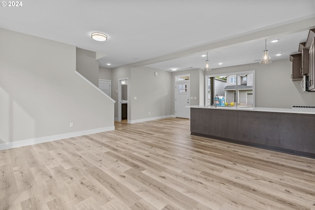 unfurnished living room featuring sink and light hardwood / wood-style floors