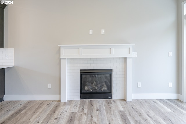 interior details with light wood-type flooring and a brick fireplace