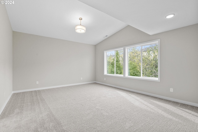 carpeted empty room featuring vaulted ceiling