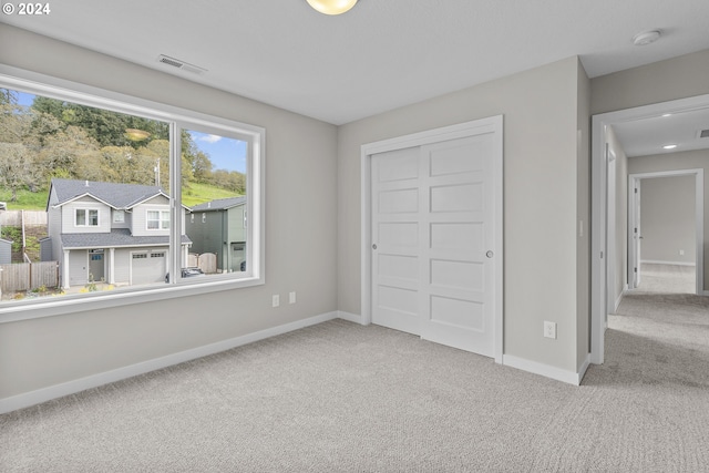 unfurnished bedroom featuring light carpet and a closet