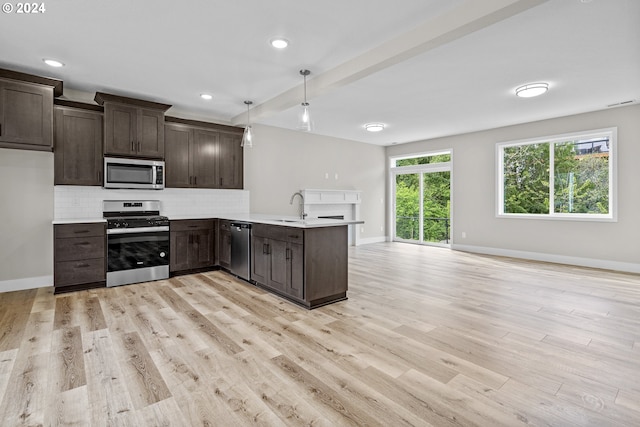 kitchen featuring backsplash, appliances with stainless steel finishes, light hardwood / wood-style flooring, and decorative light fixtures