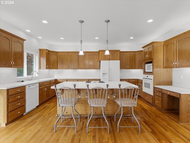 12405 SW Poppy Dr, Gaston, OR 97119 - kitchen with white appliances, a kitchen island, a sink, light wood-type flooring, and a breakfast bar area