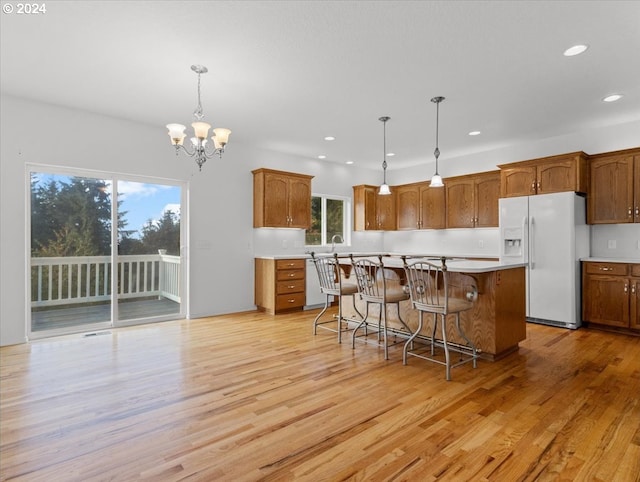 12405 SW Poppy Dr, Gaston, OR 97119 - kitchen featuring white refrigerator with ice dispenser, a chandelier, brown cabinets, light wood-type flooring, and recessed lighting