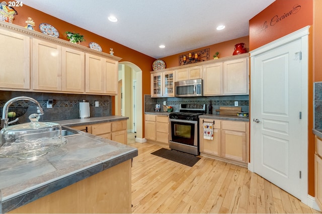 kitchen featuring sink, light hardwood / wood-style flooring, light brown cabinetry, tasteful backsplash, and stainless steel appliances