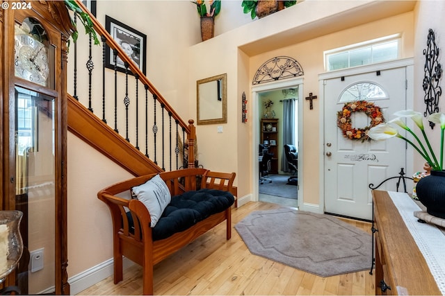 foyer entrance featuring a towering ceiling and light wood-type flooring