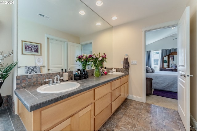 bathroom featuring vanity, backsplash, and vaulted ceiling