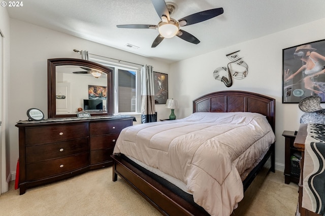 carpeted bedroom featuring ceiling fan and a textured ceiling