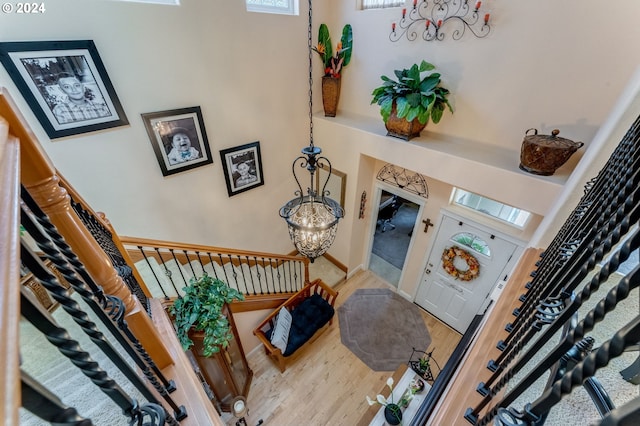 entryway featuring wood-type flooring, a high ceiling, and an inviting chandelier