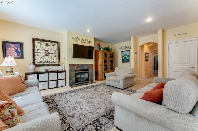 living room with a tiled fireplace and light carpet