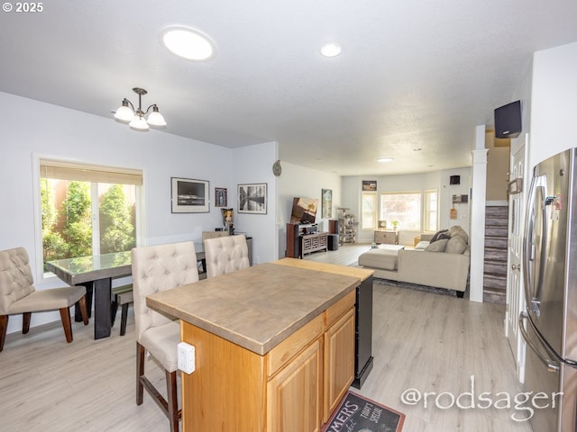 kitchen featuring a kitchen breakfast bar, light hardwood / wood-style flooring, stainless steel refrigerator, and a wealth of natural light