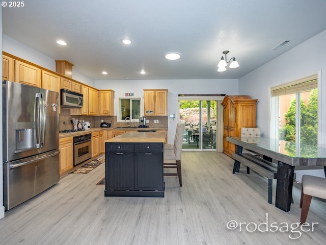 kitchen featuring a chandelier, decorative backsplash, stainless steel appliances, and light hardwood / wood-style floors