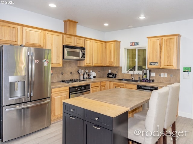 kitchen with light brown cabinetry, sink, a center island, and stainless steel appliances