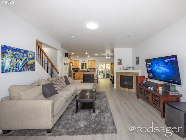 living room with a tiled fireplace and light hardwood / wood-style floors