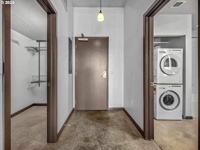 clothes washing area with stacked washing maching and dryer, baseboards, and visible vents