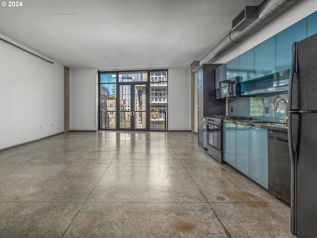 kitchen featuring dark countertops, gas stove, freestanding refrigerator, and finished concrete floors