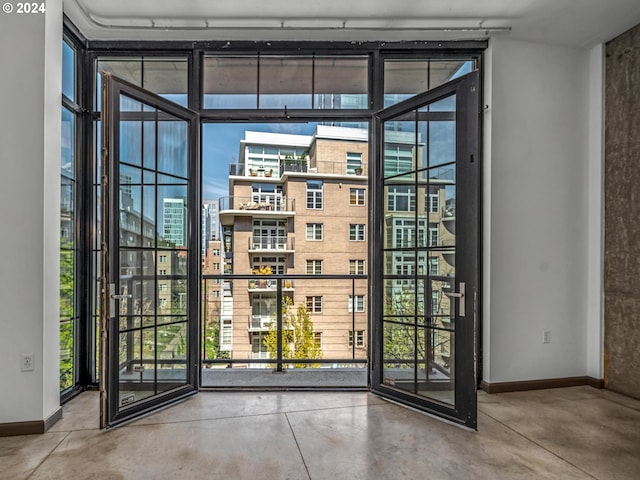 doorway with finished concrete floors, baseboards, and a city view