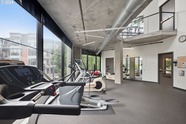 gym featuring a towering ceiling and plenty of natural light