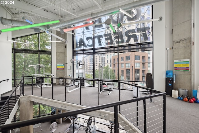 interior space featuring carpet floors, a high ceiling, and a wall of windows