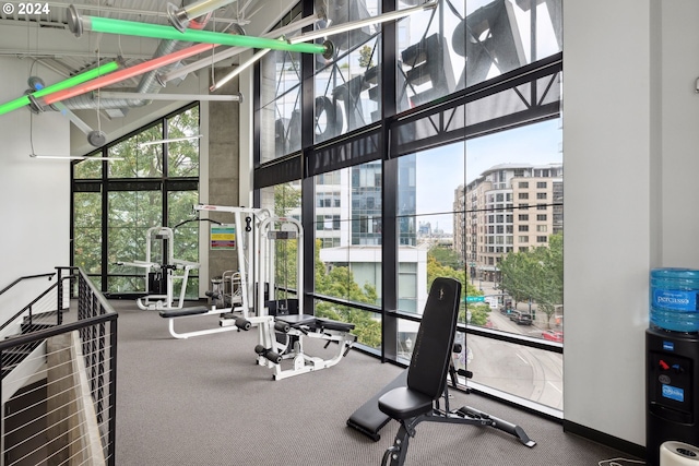 workout area with a city view, a towering ceiling, and floor to ceiling windows