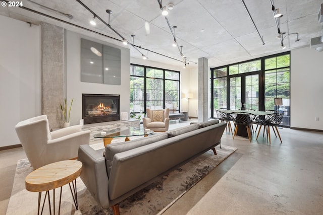 living room with a glass covered fireplace, french doors, finished concrete flooring, and track lighting