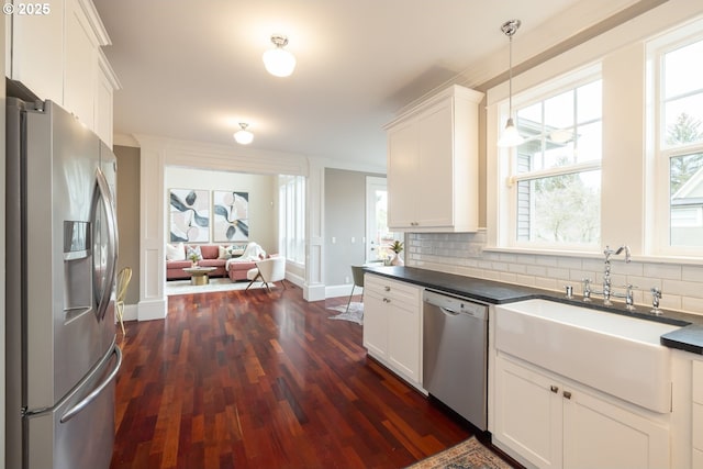 kitchen with white cabinetry, appliances with stainless steel finishes, decorative backsplash, and decorative light fixtures