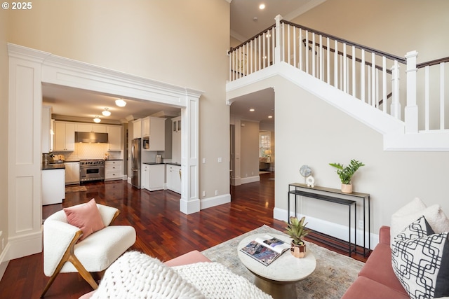 living room with a towering ceiling and dark hardwood / wood-style flooring