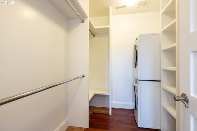 walk in closet featuring stacked washing maching and dryer and dark hardwood / wood-style flooring