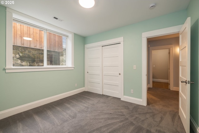 unfurnished bedroom featuring dark carpet and a closet