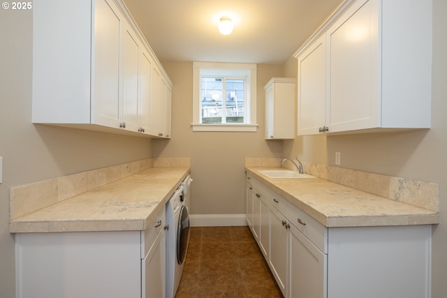 kitchen with dark tile patterned floors, white cabinetry, and sink