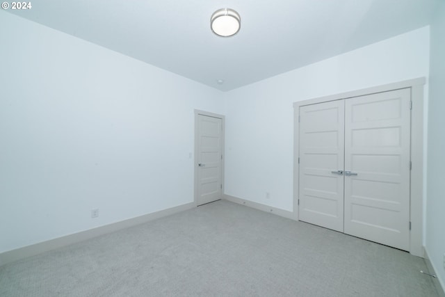 unfurnished bedroom with a closet and light colored carpet