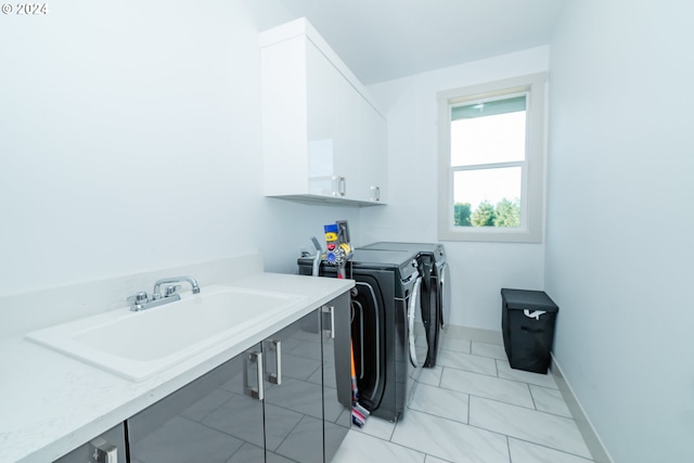 washroom featuring washing machine and clothes dryer, cabinets, and sink