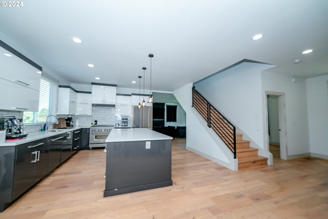 kitchen with a kitchen island, light wood-type flooring, white cabinets, hanging light fixtures, and appliances with stainless steel finishes