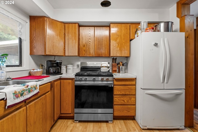 kitchen with white refrigerator, gas stove, and light hardwood / wood-style floors