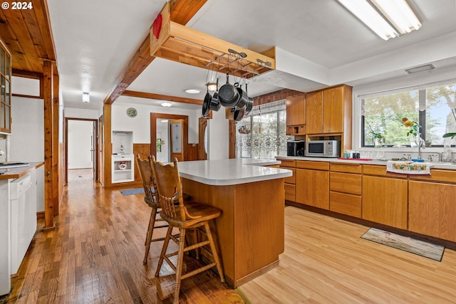 kitchen with light wood-type flooring, sink, and a breakfast bar area