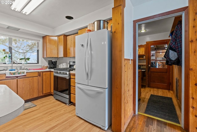 kitchen with white refrigerator, light hardwood / wood-style flooring, sink, and gas range