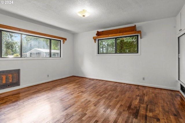 unfurnished room with a fireplace, wood-type flooring, and a textured ceiling