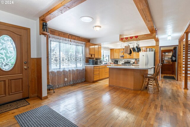 kitchen featuring range, beam ceiling, light hardwood / wood-style flooring, a kitchen island, and white fridge