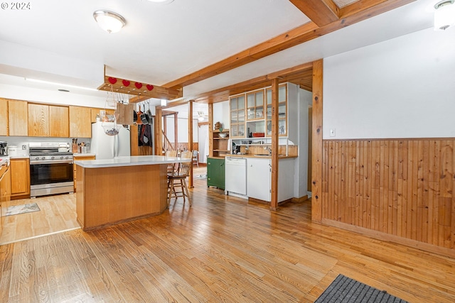 kitchen with light wood-type flooring, a kitchen breakfast bar, white appliances, and a kitchen island