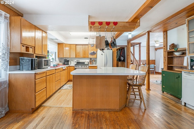 kitchen with light wood-type flooring, stainless steel appliances, a kitchen bar, and a center island