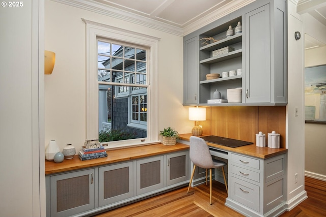 office space with hardwood / wood-style flooring, crown molding, and built in desk