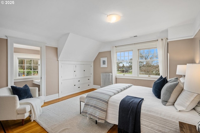 bedroom featuring lofted ceiling, radiator, and hardwood / wood-style floors