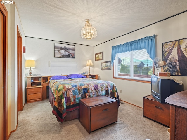 bedroom with a notable chandelier, a textured ceiling, and light colored carpet