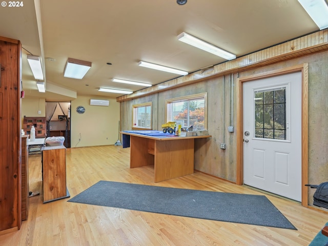 interior space with a kitchen breakfast bar, light hardwood / wood-style flooring, and a wall mounted air conditioner